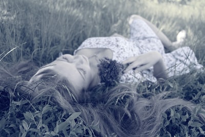 女人在白天的粉色长裙躺在草地上
